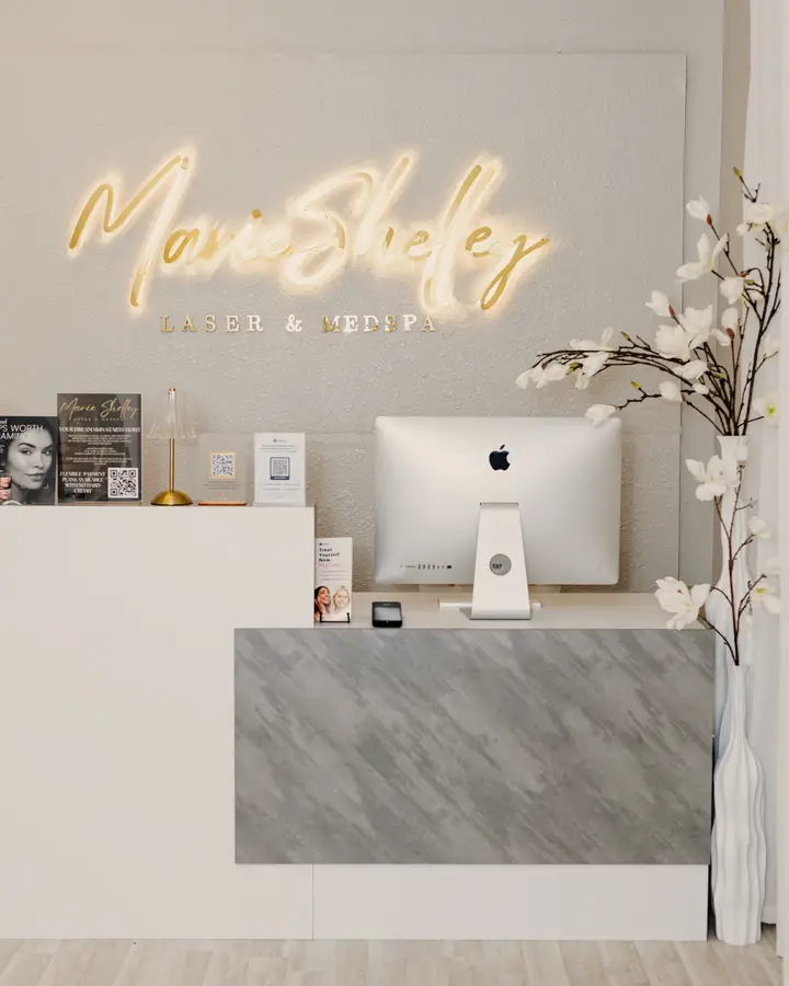 The studio reception: the lit gold Marie Shelley sign above a white desk.